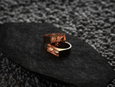 Angled shot of the rose-gold plated ring, accentuating the twin skull carvings and thin bezel border.