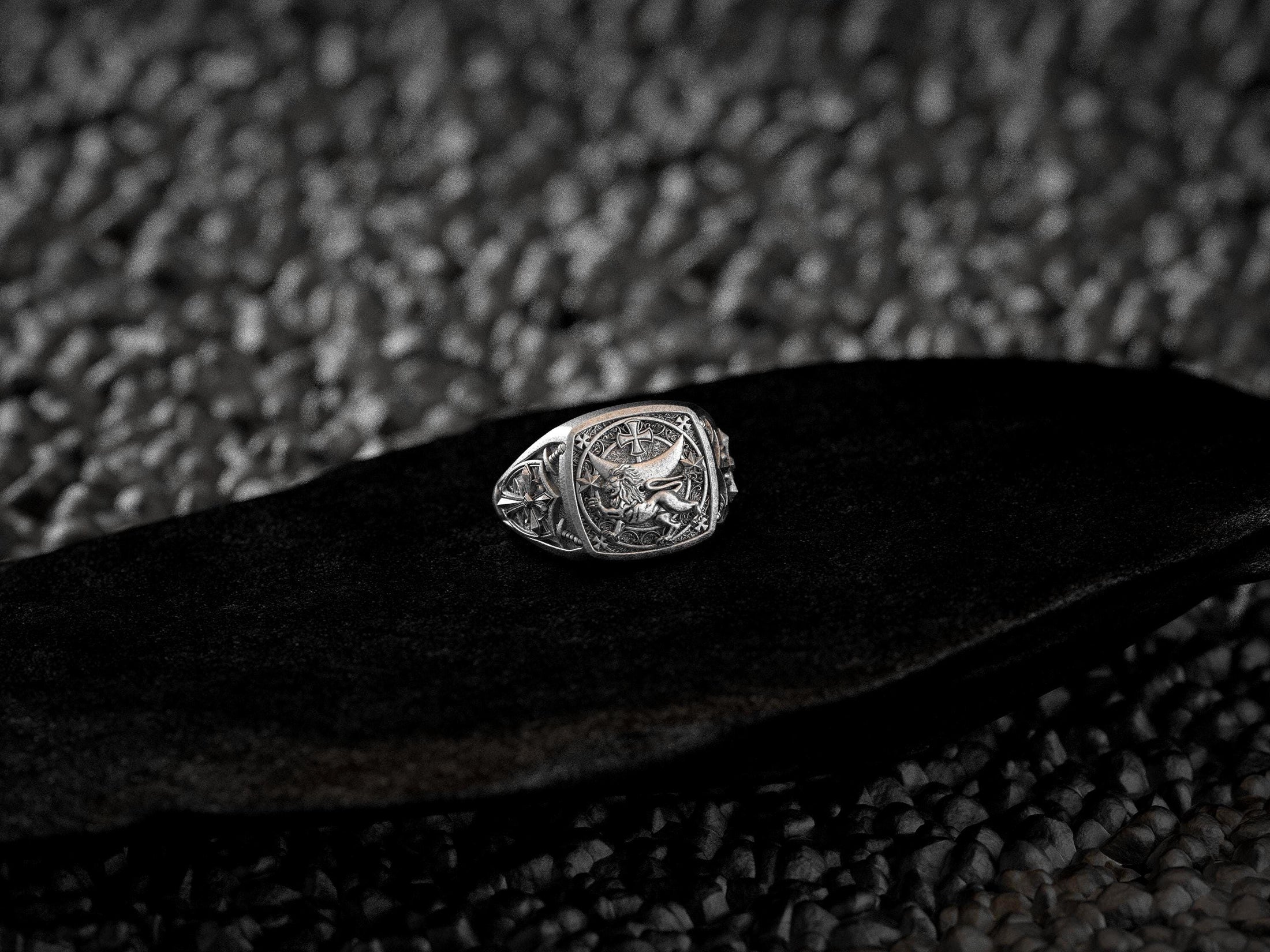 Close-up of lion with crescent moon, cross, and star details on ring