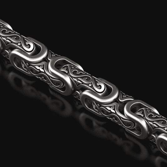 Close-up of oxidized scrollwork chain links with baroque details