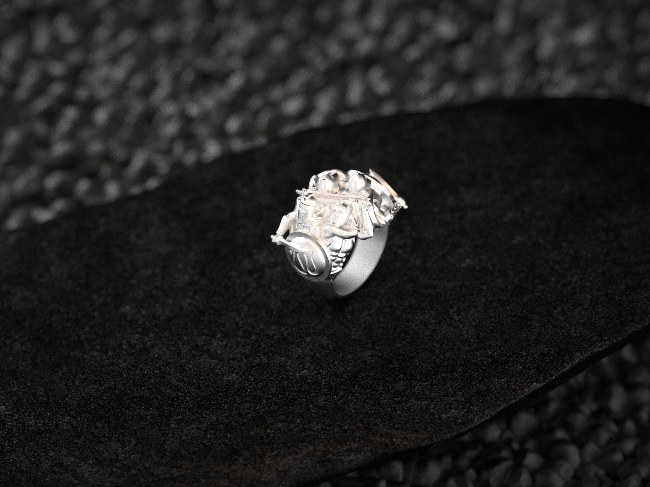 “High-polish 925 silver Spartan Phalanx signet ring angled on dark stone, highlighting sculpted helmets, shields, and crossed spears.”