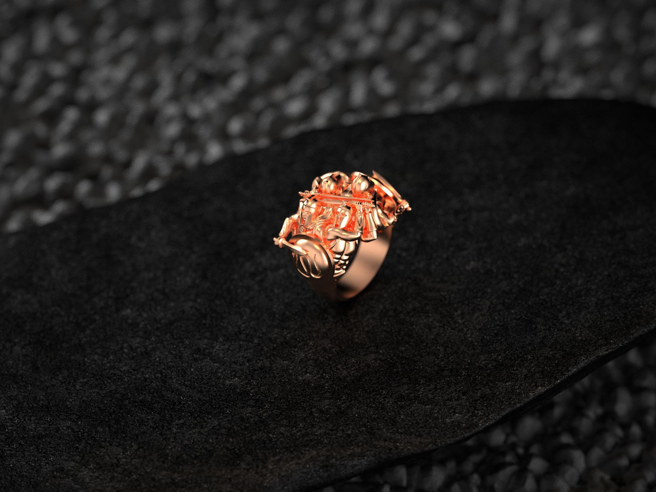 “Rose-gold Spartan Phalanx signet ring on dark pebble-textured surface, showcasing polished hoplite helmets and muscled torsos.”