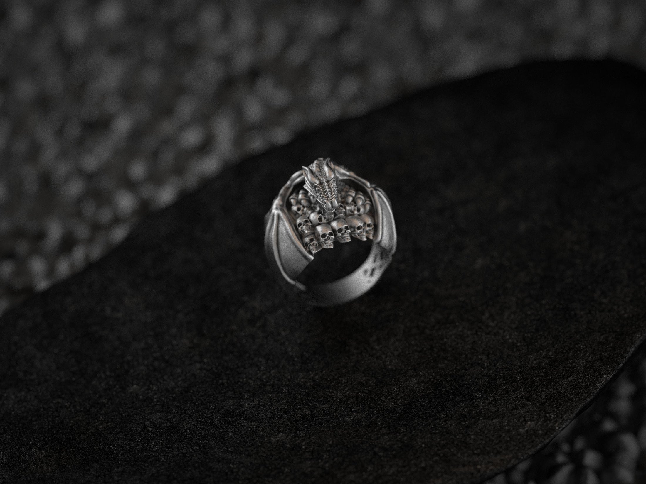Angled view of silver ring on dark stone pedestal.