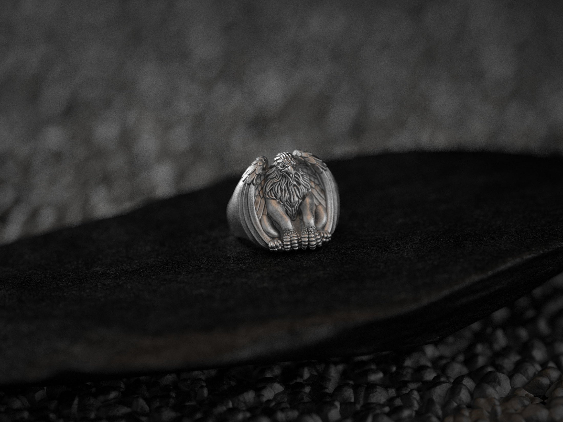 Angled view of silver griffin ring showcasing detailed feathers and claws.