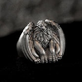 Close-up of sterling silver griffin signet ring on black stone.