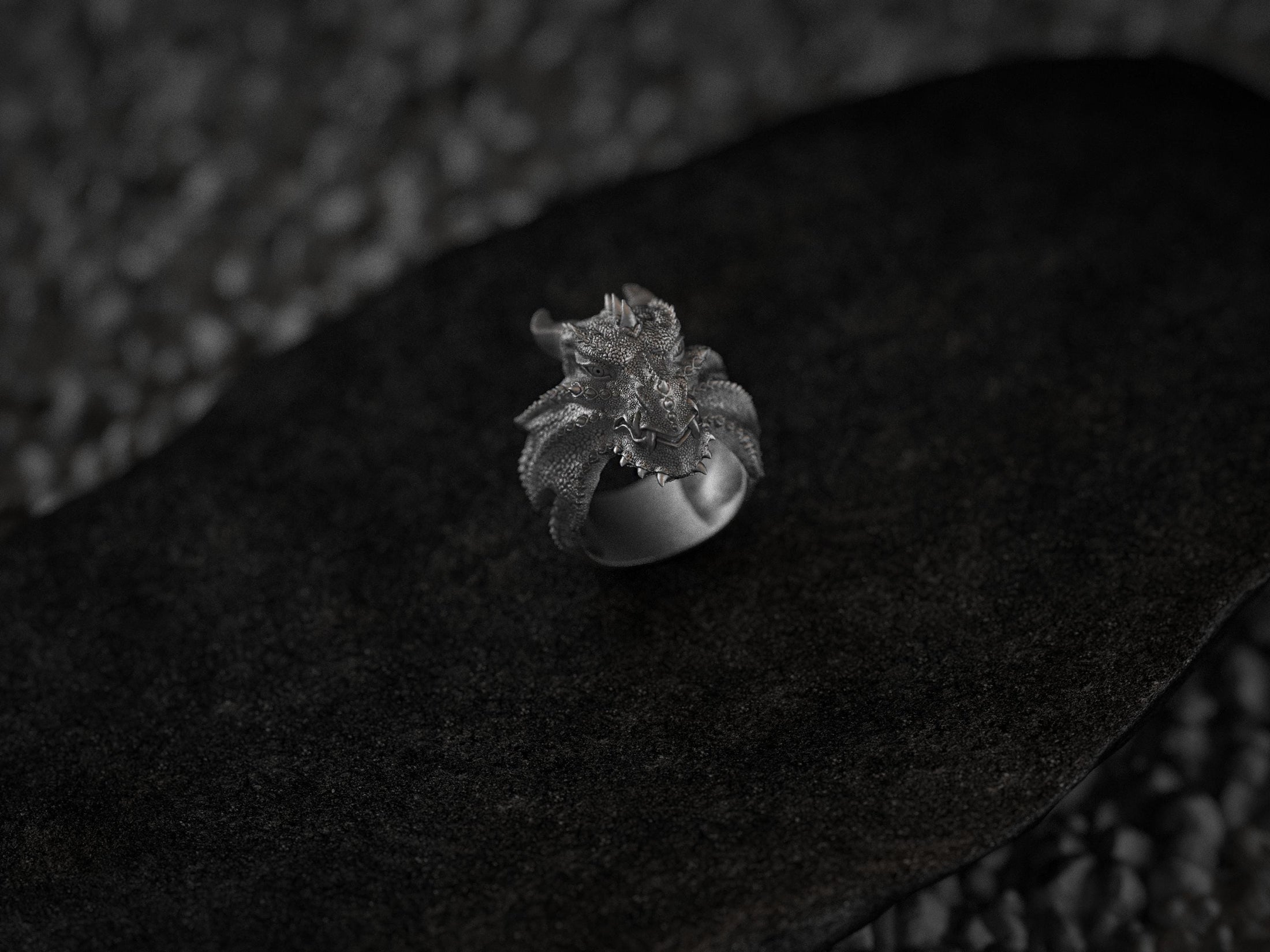 Close-up of the sterling silver Dragon Wyrm Scales ring perched on a smooth black stone.