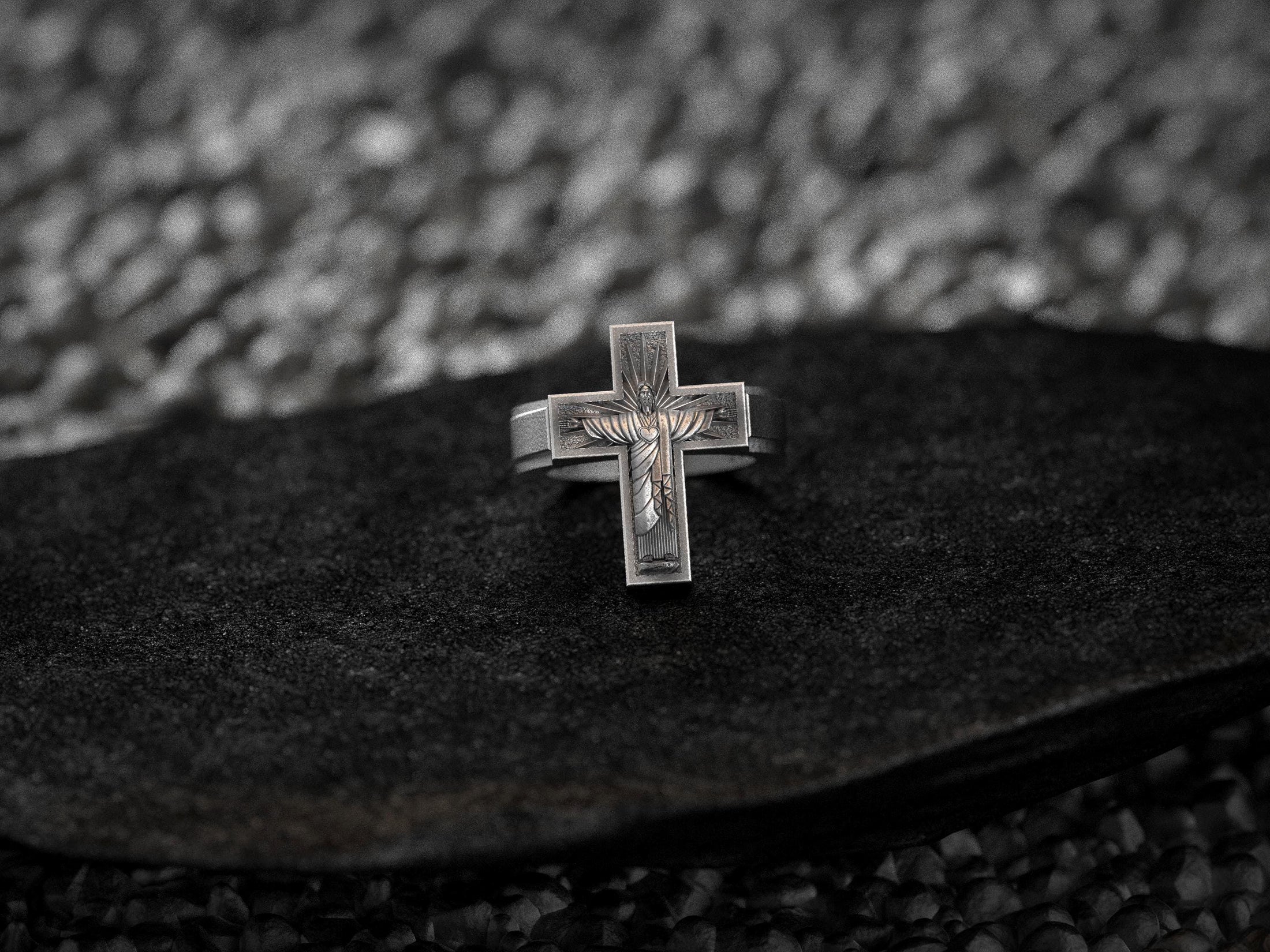 Close-up macro of the silver Christ relief, highlighting the textured radiating background within the cross arms.
