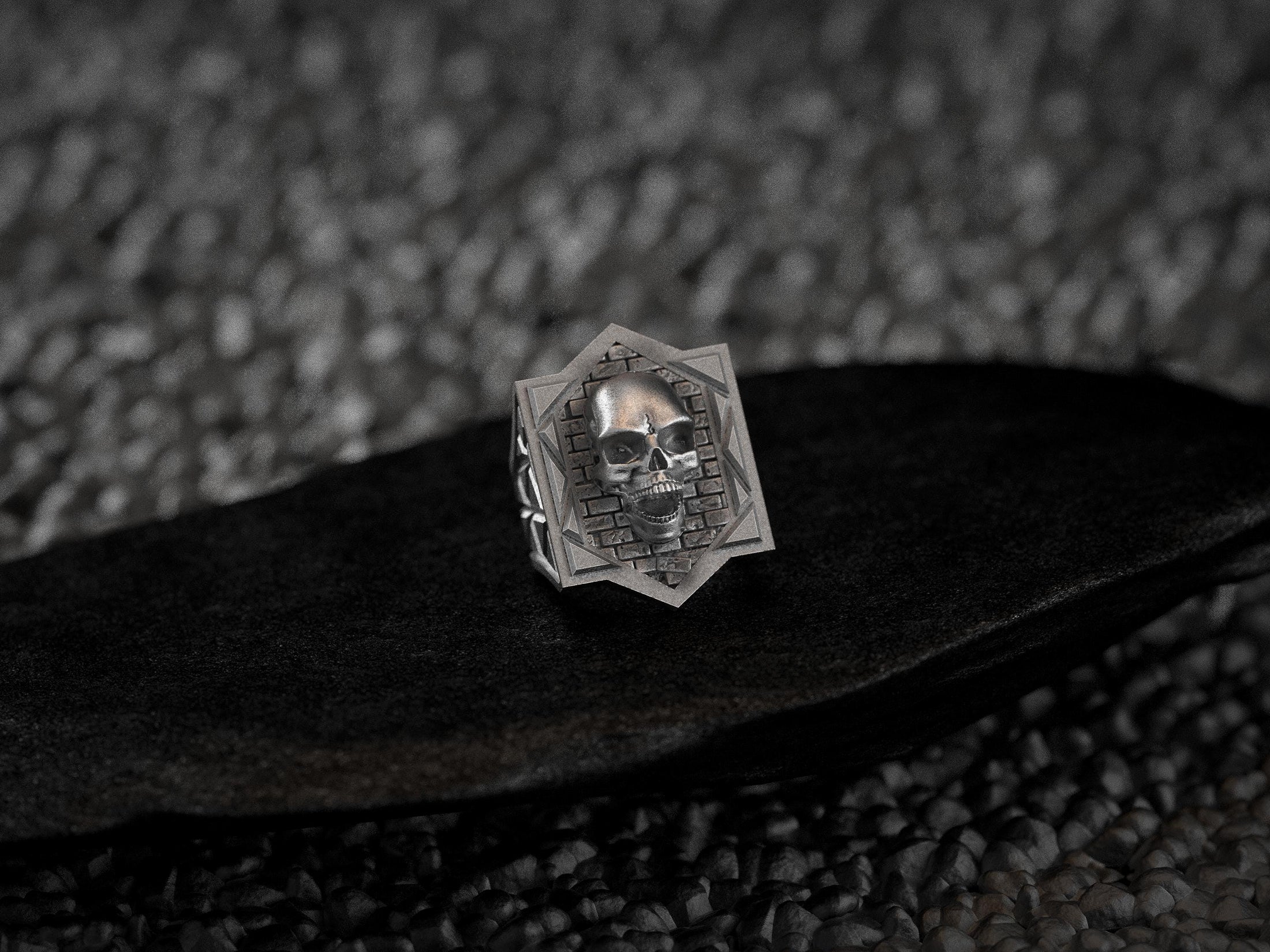 Three-quarter angle of the silver ring highlighting the raised skull’s hollow eyes and toothy grin atop the textured bricks.
