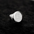 Bild in Galerie-Betrachter laden, May include: A silver signet ring with a circular, textured top featuring an etched design. The ring has a classic style and is displayed on a dark gray surface. The detailed engraving on the face of the ring is visible.
