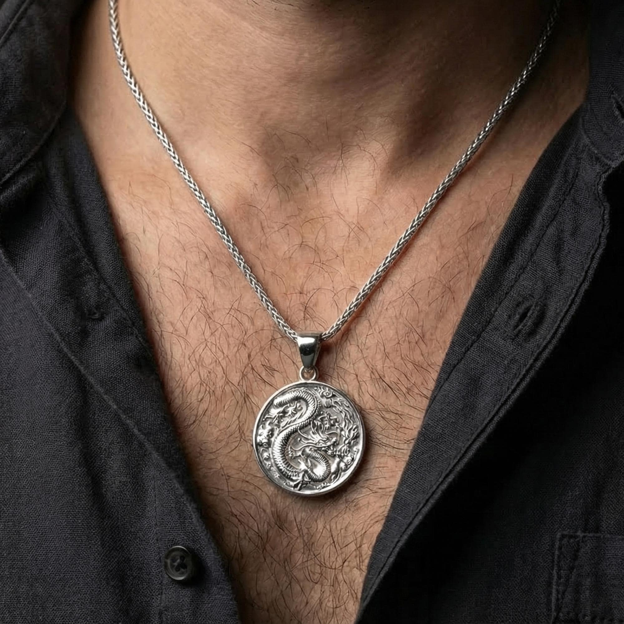 Polished silver dragon coin necklace worn on chest showing detailed dragon symbol jewelry