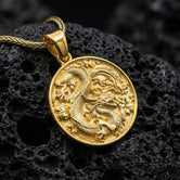Gold plated dragon medallion necklace round dragon pendant photographed on volcanic rock surface