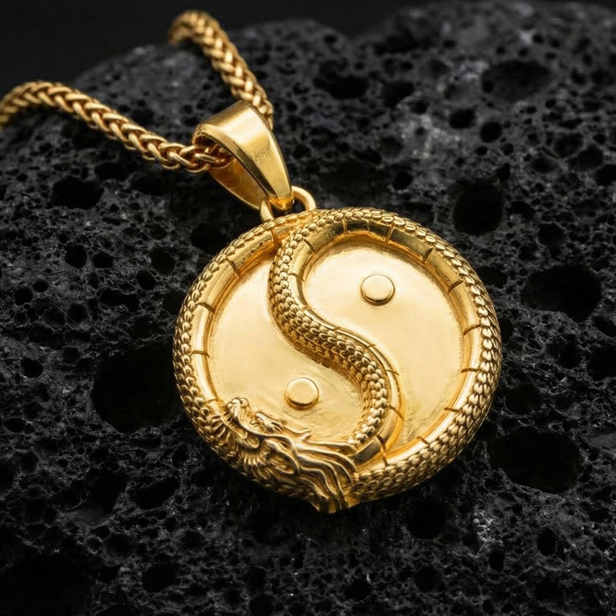 Gold plated yin yang dragon pendant necklace symbolizing balance on volcanic stone surface