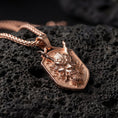 Load image into Gallery viewer, Rose gold plated oni mask dragon dog tag necklace presented on volcanic rock surface with dark mythic aesthetic
