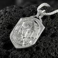 Load image into Gallery viewer, Polished silver gothic dragon shield pendant necklace displayed on volcanic stone background with sharp sculpted relief
