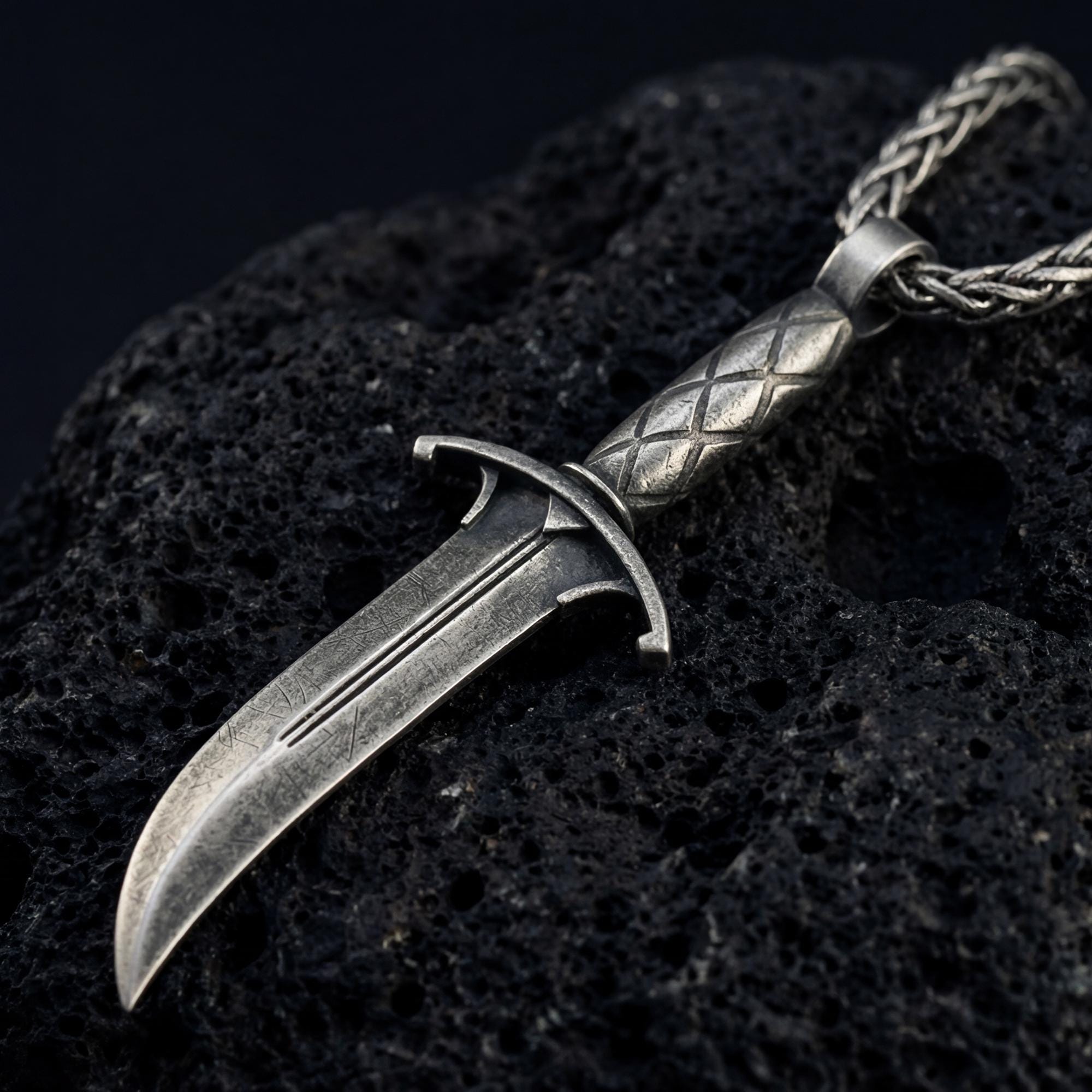 Oxidized Astarion dagger pendant necklace photographed on volcanic rock with distressed vampire blade detail