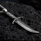 Oxidized Astarion dagger pendant necklace photographed on volcanic rock with distressed vampire blade detail
