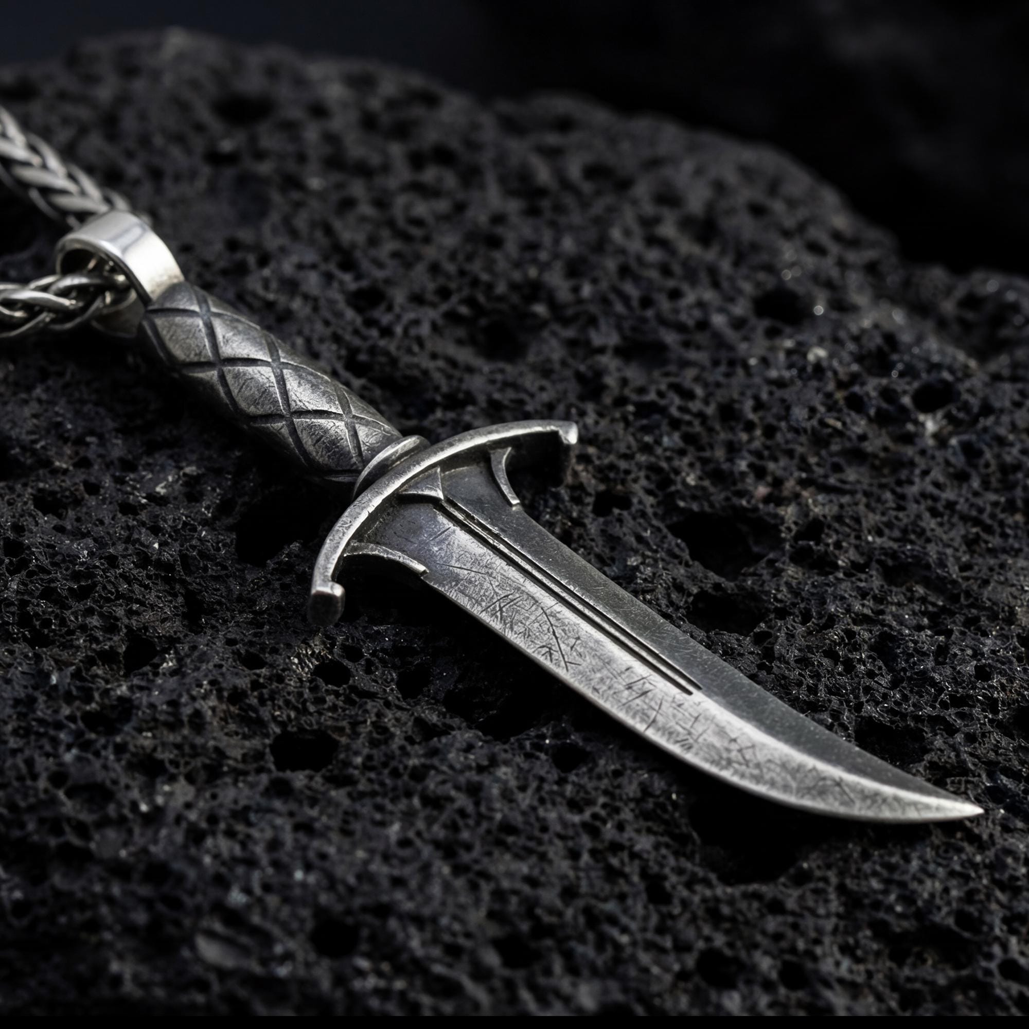 Oxidized Astarion dagger pendant necklace photographed on volcanic rock with distressed vampire blade detail