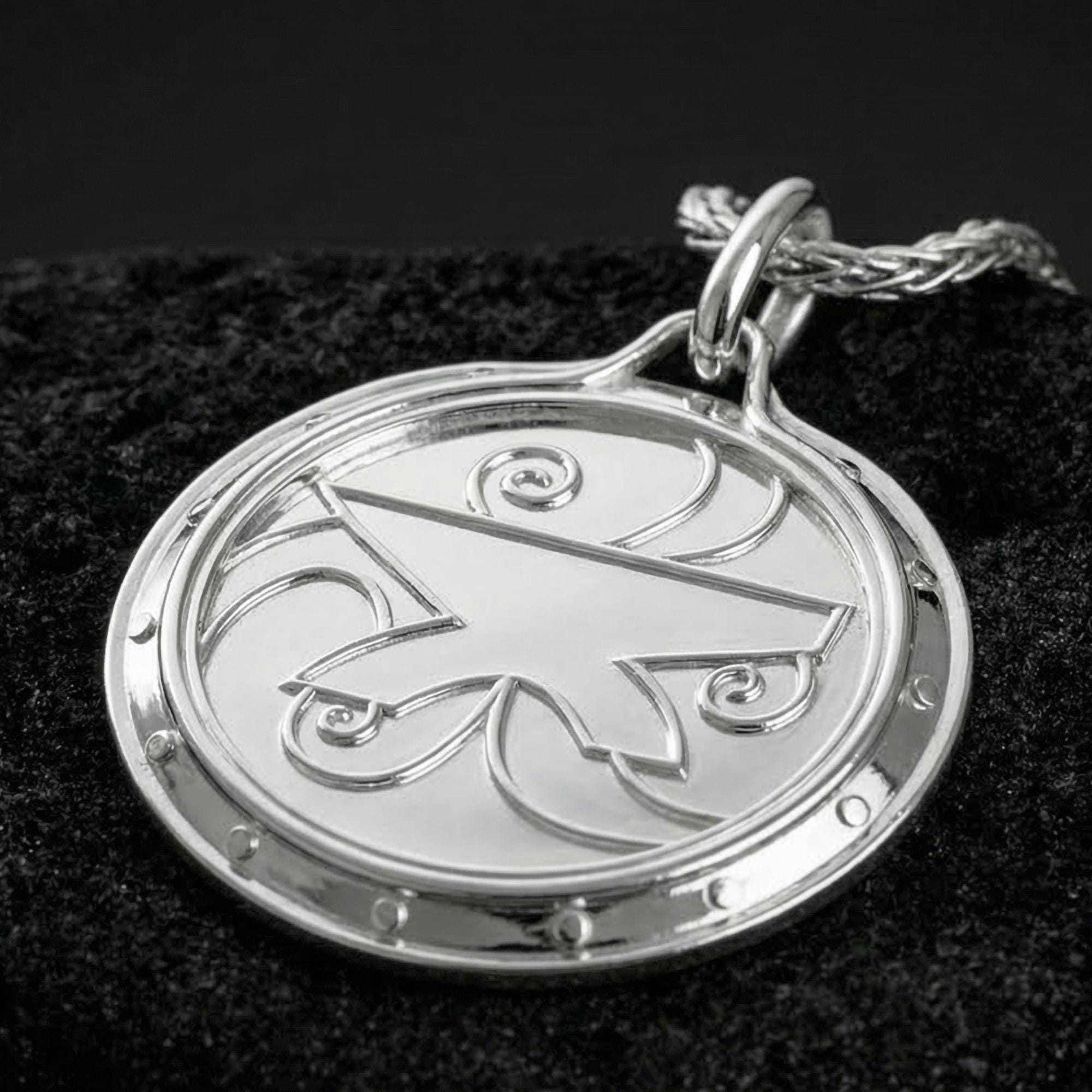 Polished silver Zenithar amulet necklace displayed on volcanic stone background with clean Nordic relief detail