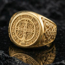 Gold plated St Benedict signet ring on dark volcanic rock, Benedict medal seal with lettering, Catholic spiritual protection ring