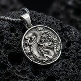 Oxidized silver dragon medallion pendant necklace with coiled dragon design on volcanic rock background