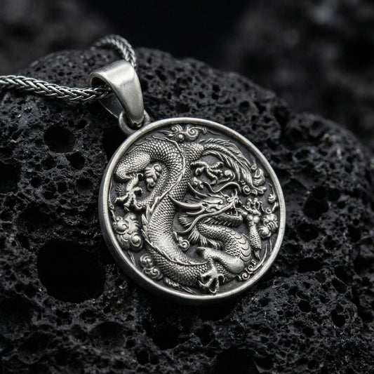 Oxidized silver dragon medallion pendant necklace with coiled dragon design on volcanic rock background