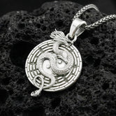 Polished silver yin yang dragon medallion necklace featuring taoist balance symbol on volcanic stone background