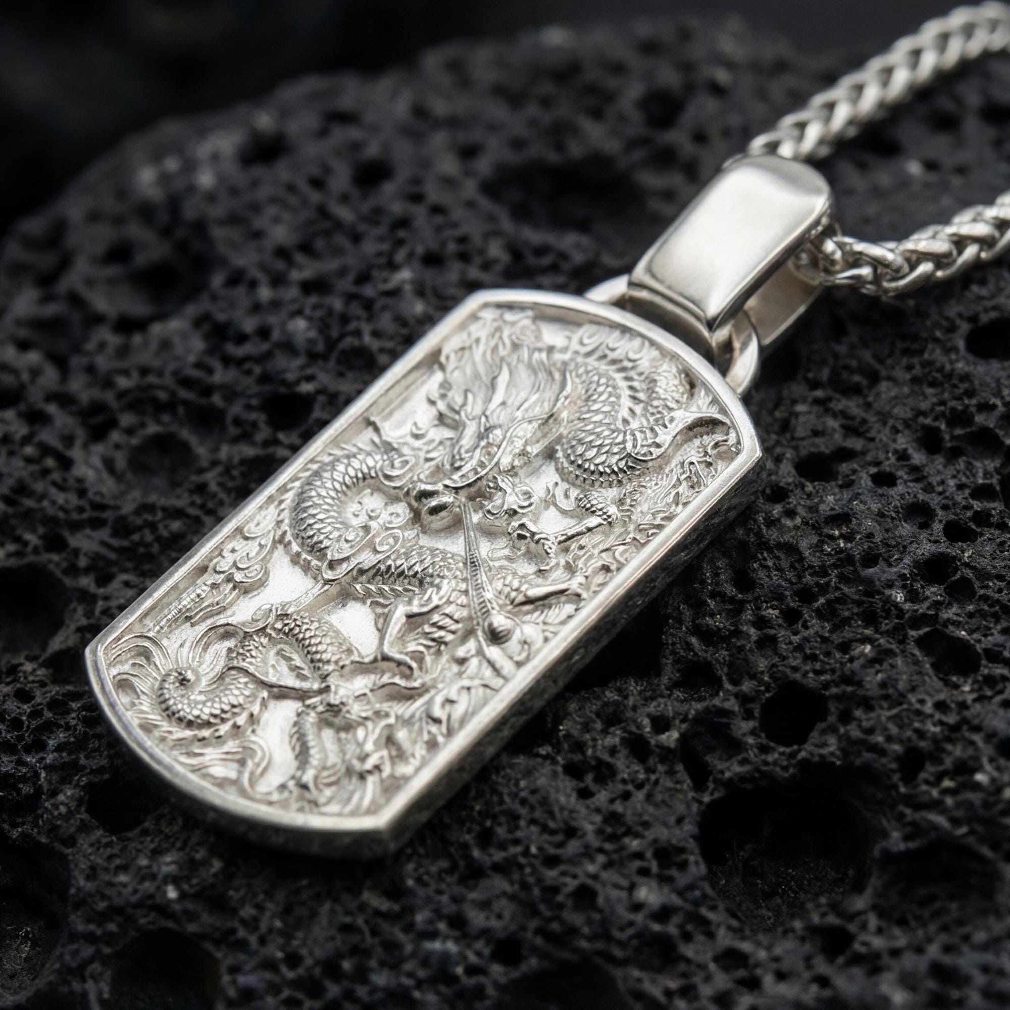 Polished silver chinese dragon dog tag necklace on volcanic stone background with mythic relief