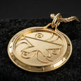 Load image into Gallery viewer, Gold plated Amulet of Zenithar pendant showcased on volcanic rock as a symbol of wealth and prosperity
