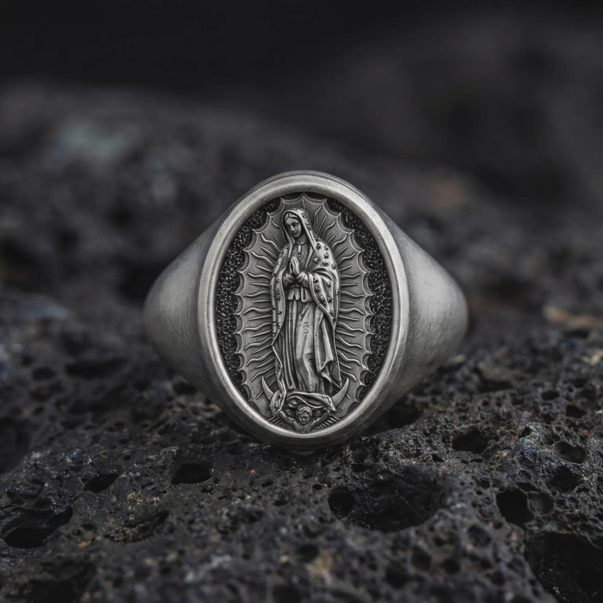 Oxidized Our Lady of Guadalupe signet ring in sterling silver photographed on volcanic rock background