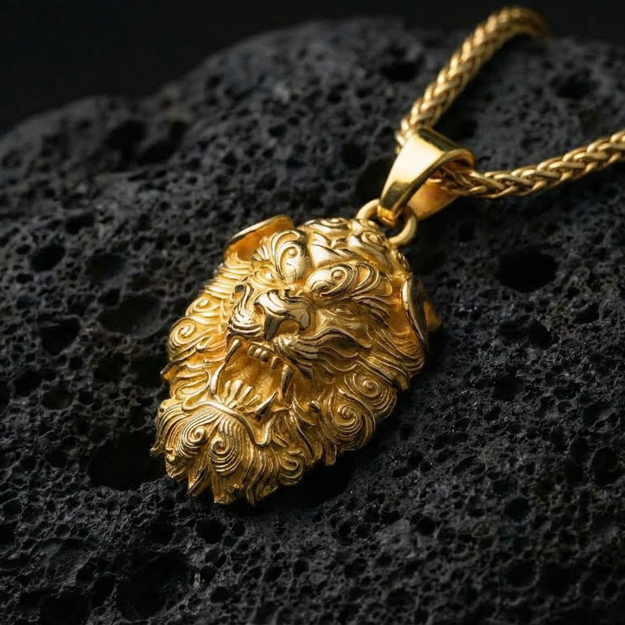 Gold plated Fu Dog guardian lion pendant showcased on volcanic rock as a symbol of protection and strength