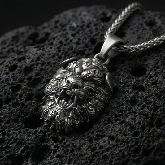 Oxidized Fu Dog pendant necklace photographed on volcanic rock with detailed Chinese guardian lion relief