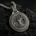 Load image into Gallery viewer, Oxidized Yggdrasil tree of life pendant necklace photographed on volcanic rock with detailed Norse knotwork roots and branches
