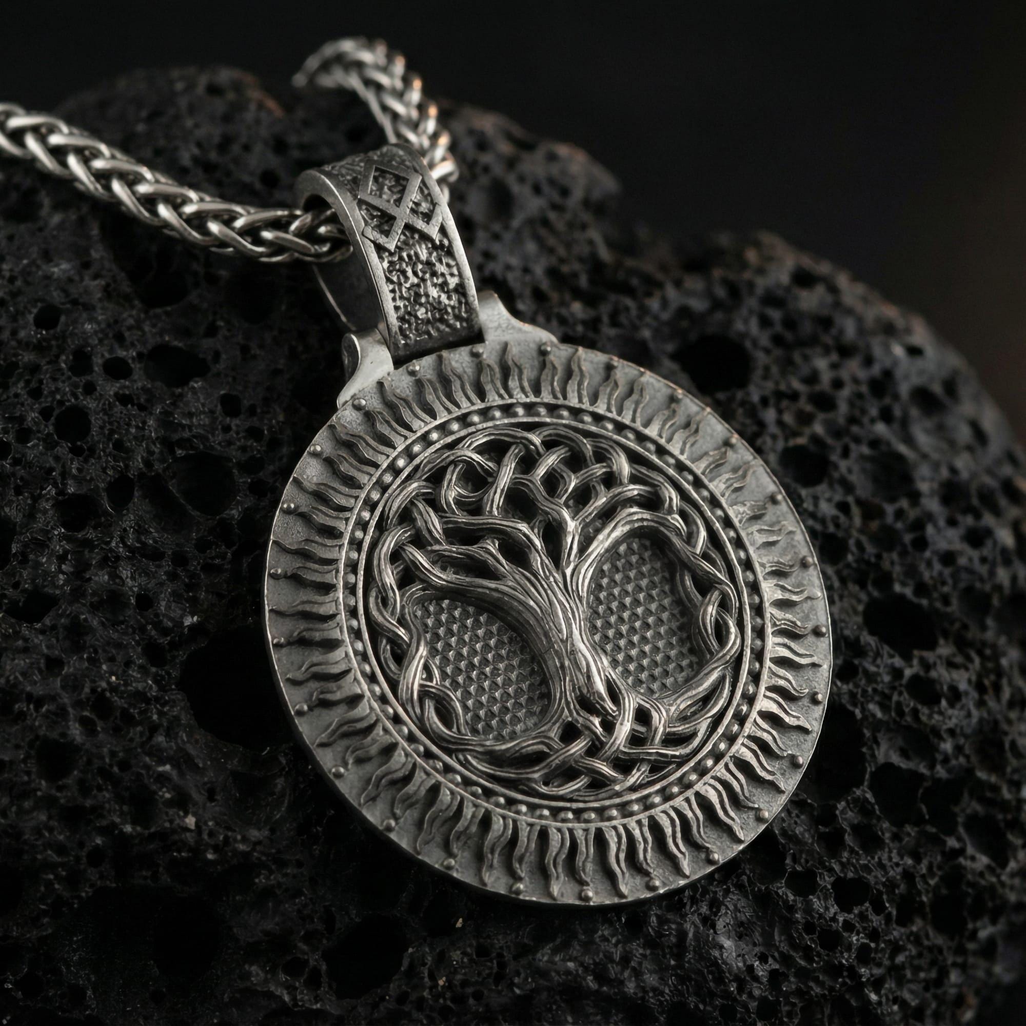 Oxidized Yggdrasil tree of life pendant necklace photographed on volcanic rock with detailed Norse knotwork roots and branches