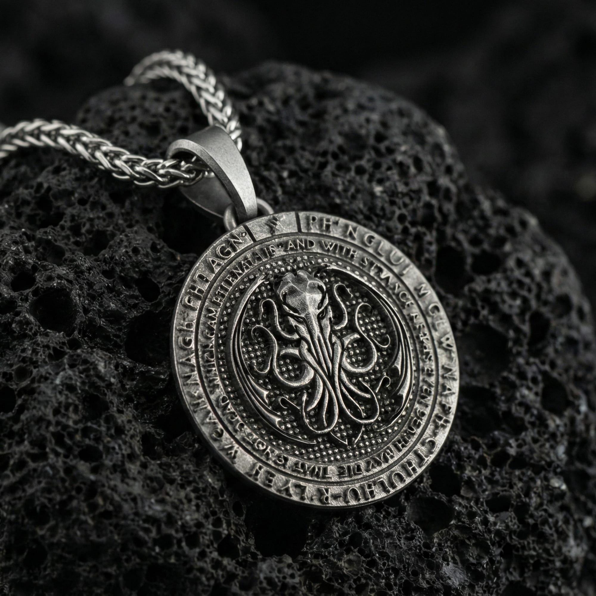 Oxidized Cthulhu pendant necklace photographed on volcanic rock with engraved Lovecraftian octopus sigil and eldritch detail