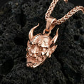 Load image into Gallery viewer, Rose gold plated Japanese demon oni pendant necklace presented on volcanic rock surface with dark samurai aesthetic
