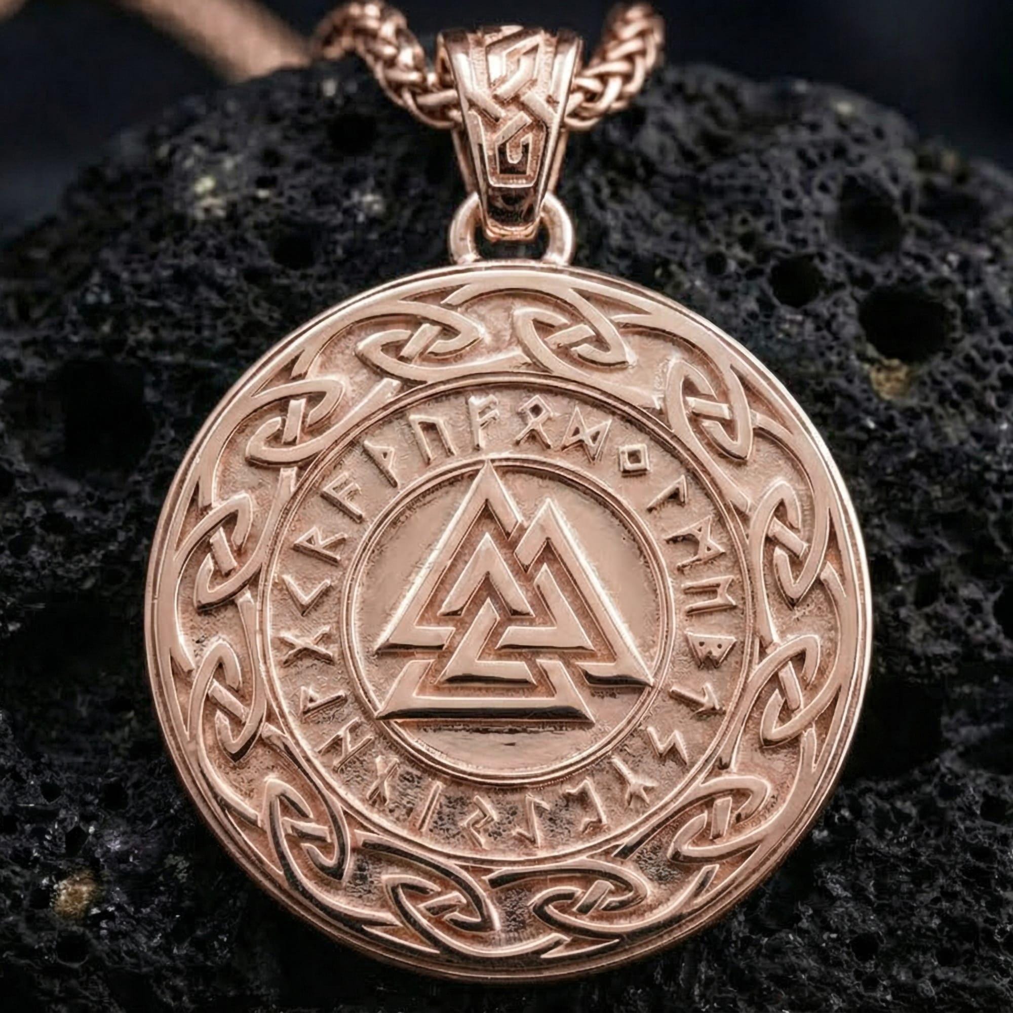 Rose gold plated Norse Valknut rune pendant necklace presented on volcanic rock surface with dark Viking myth aesthetic