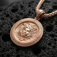 Load image into Gallery viewer, Rose gold plated Medusa Gorgon pendant presented on volcanic rock surface with classical Greek myth aesthetic
