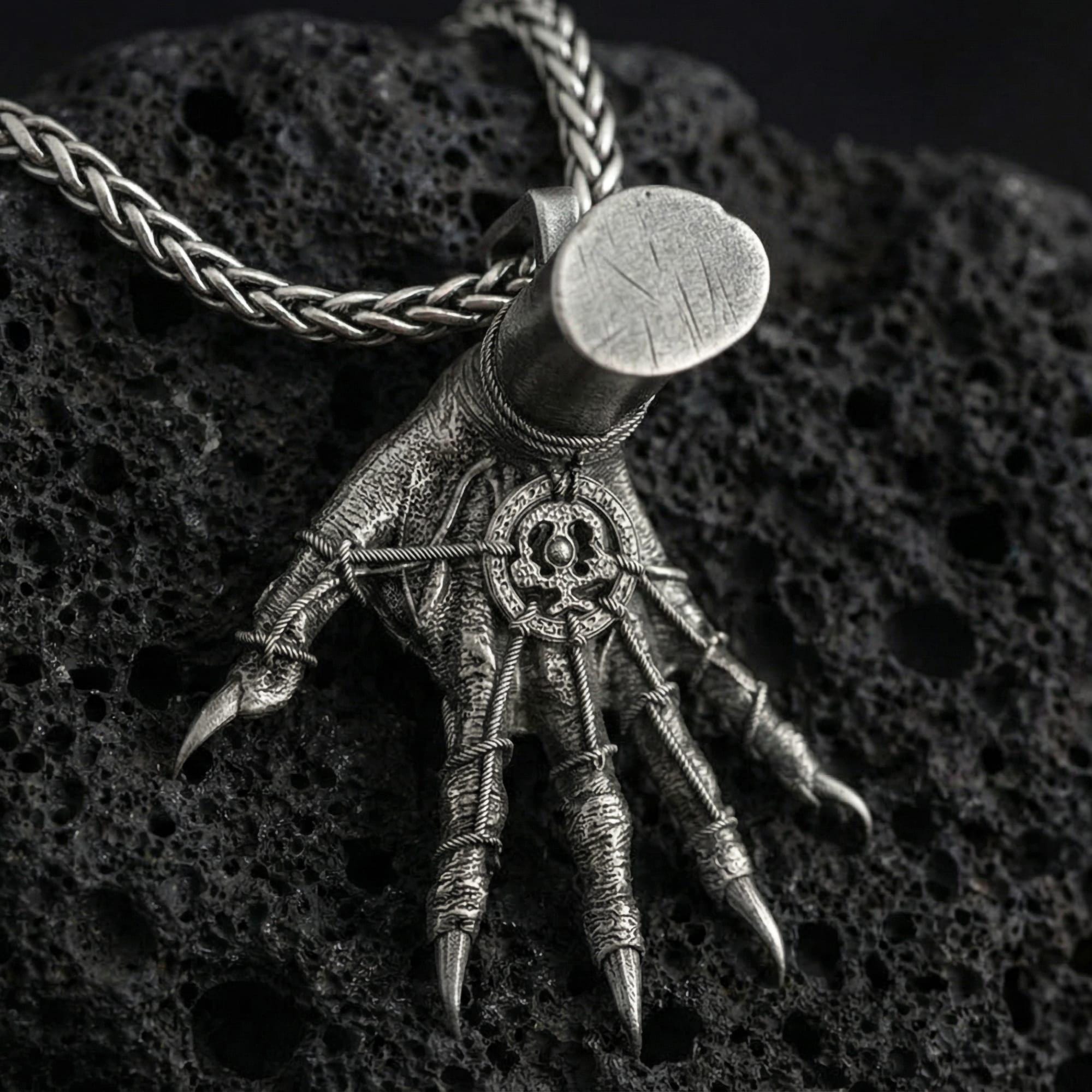 Oxidized Hand of Maliketh pendant necklace photographed on volcanic rock with detailed clawed hand relief and gothic texture
