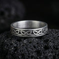 Load image into Gallery viewer, Oxidized Celtic knot ring photographed on volcanic rock with engraved endless knot pattern and dark oxidized contrast
