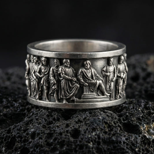 Oxidized ancient Greek philosopher band ring photographed on volcanic rock with high-relief classical figures and historical frieze detail