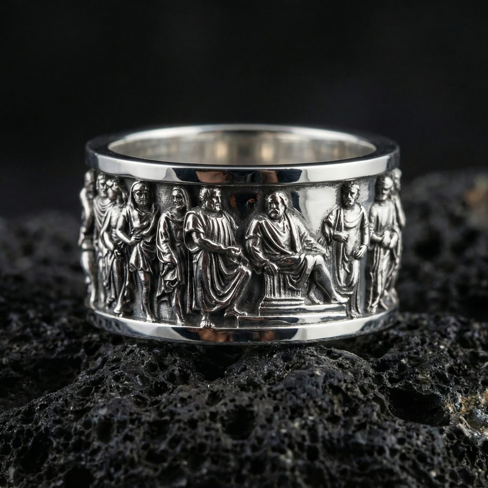 Polished silver Roman senate inspired band ring displayed on volcanic stone background highlighting sculpted human figures in procession