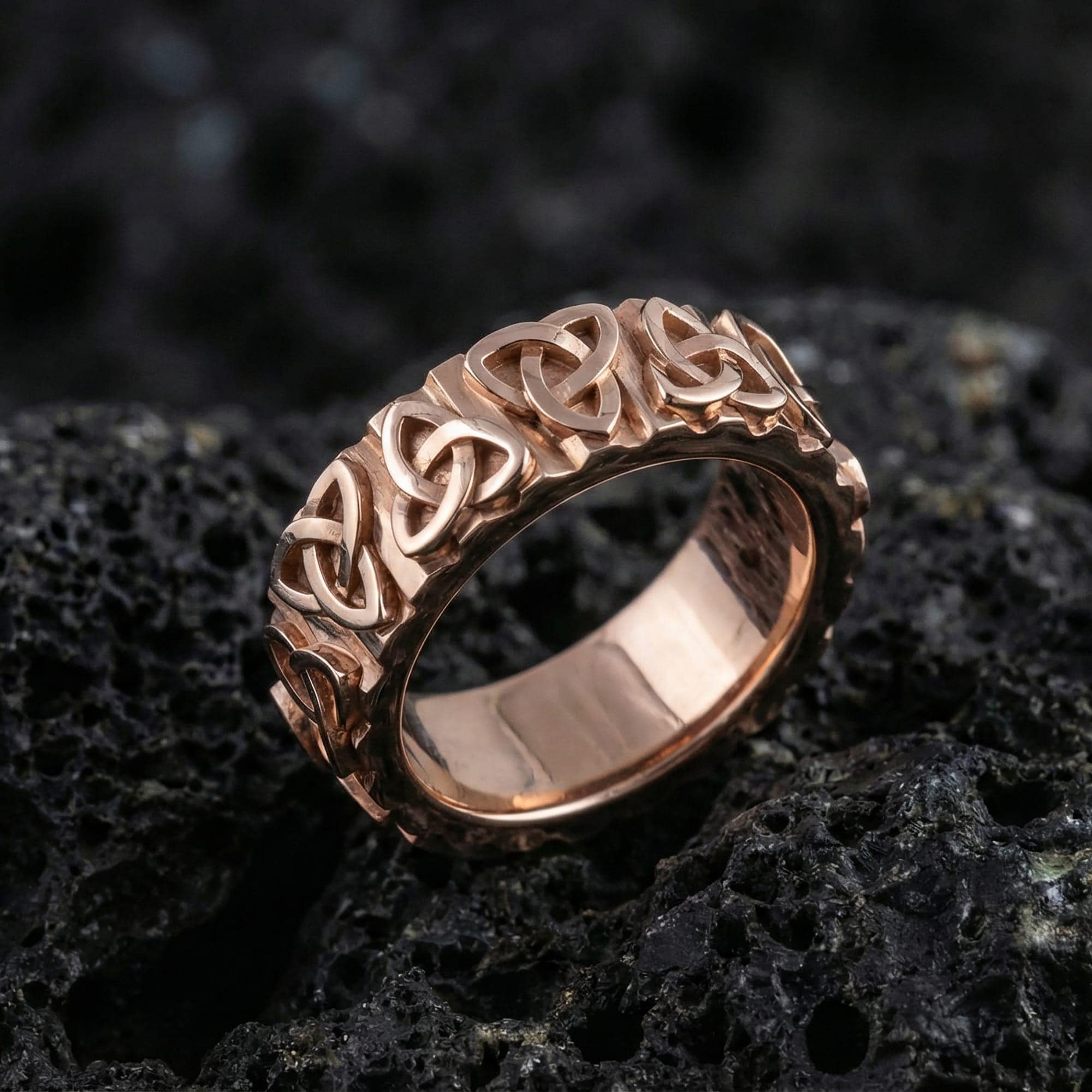 Rose gold Celtic knot eternity ring with repeating triquetra design on volcanic stone