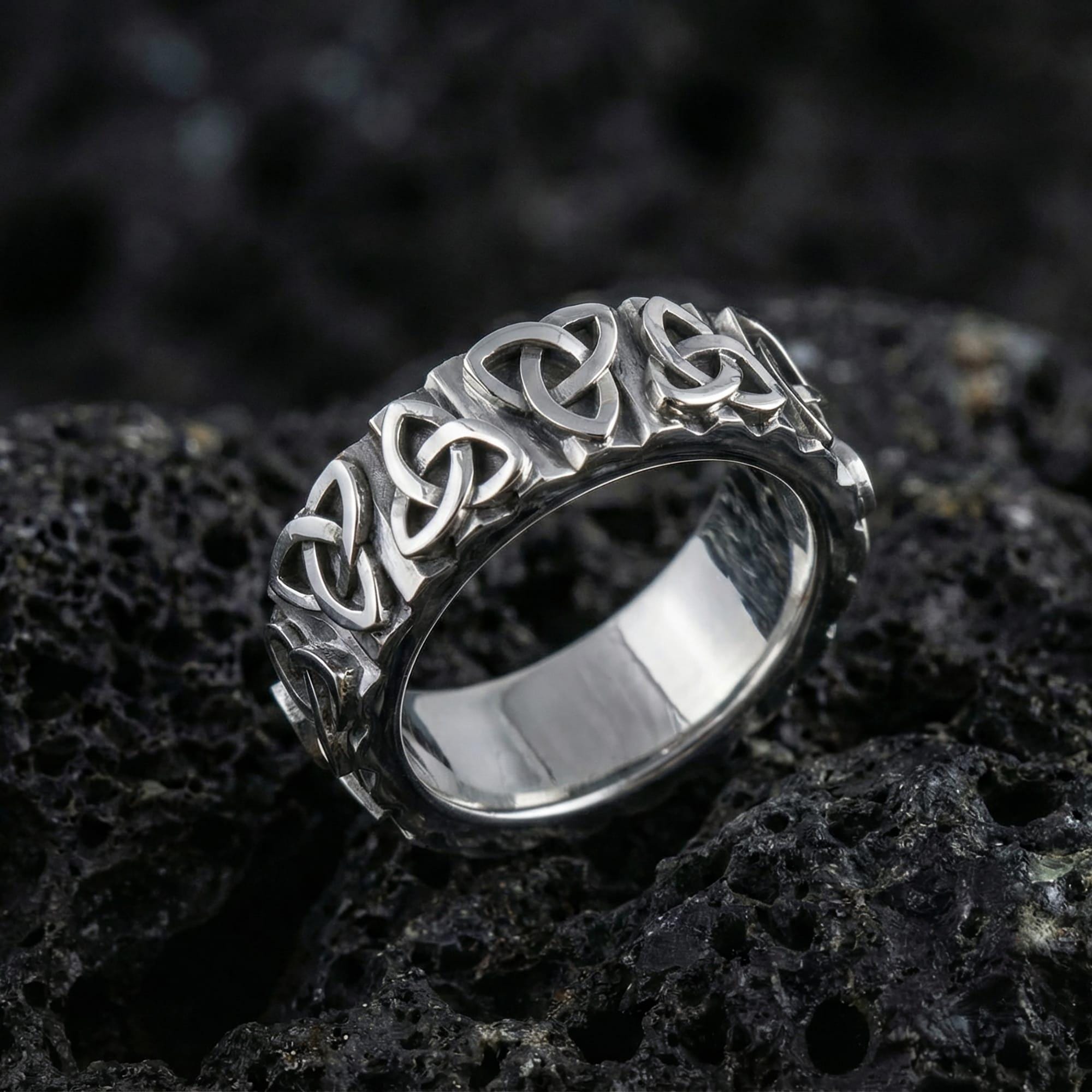 White gold Celtic knot eternity band ring with detailed triquetra pattern on volcanic stone