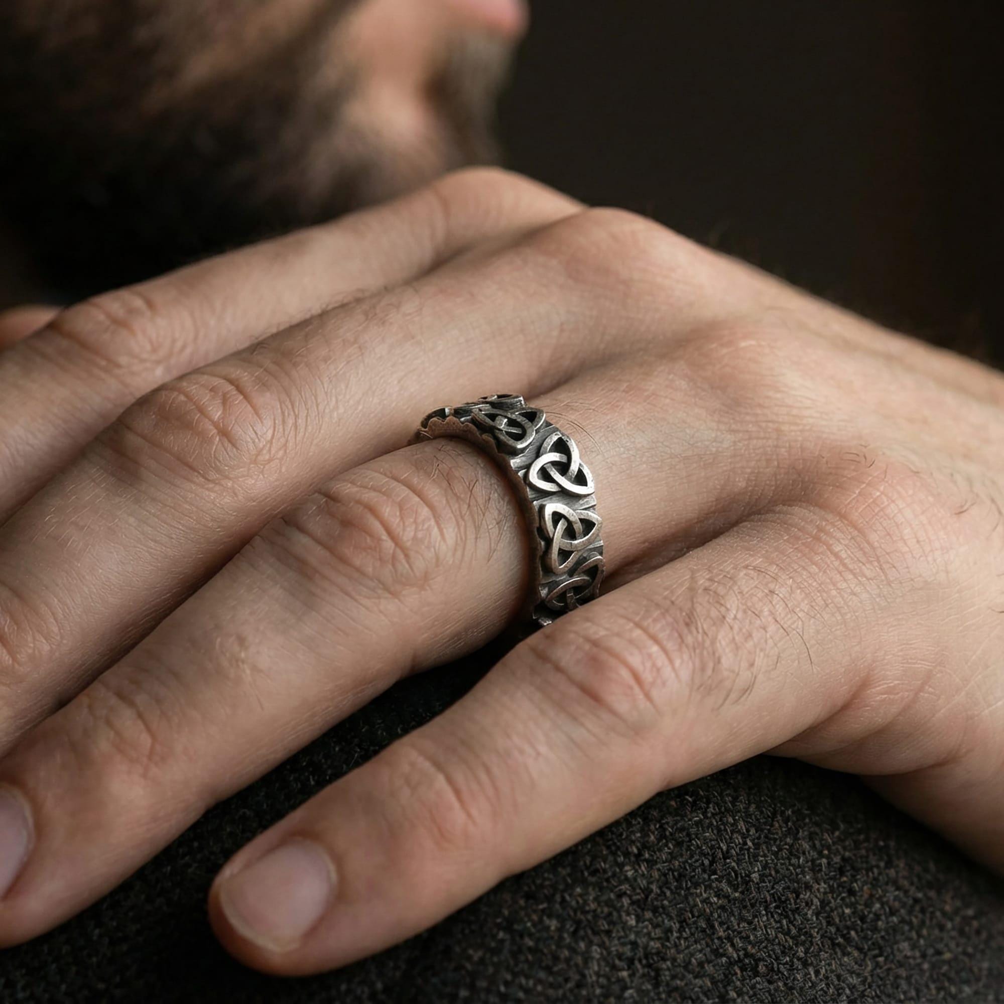 Oxidized sterling silver Celtic trinity knot band ring worn on finger as symbolic jewelry