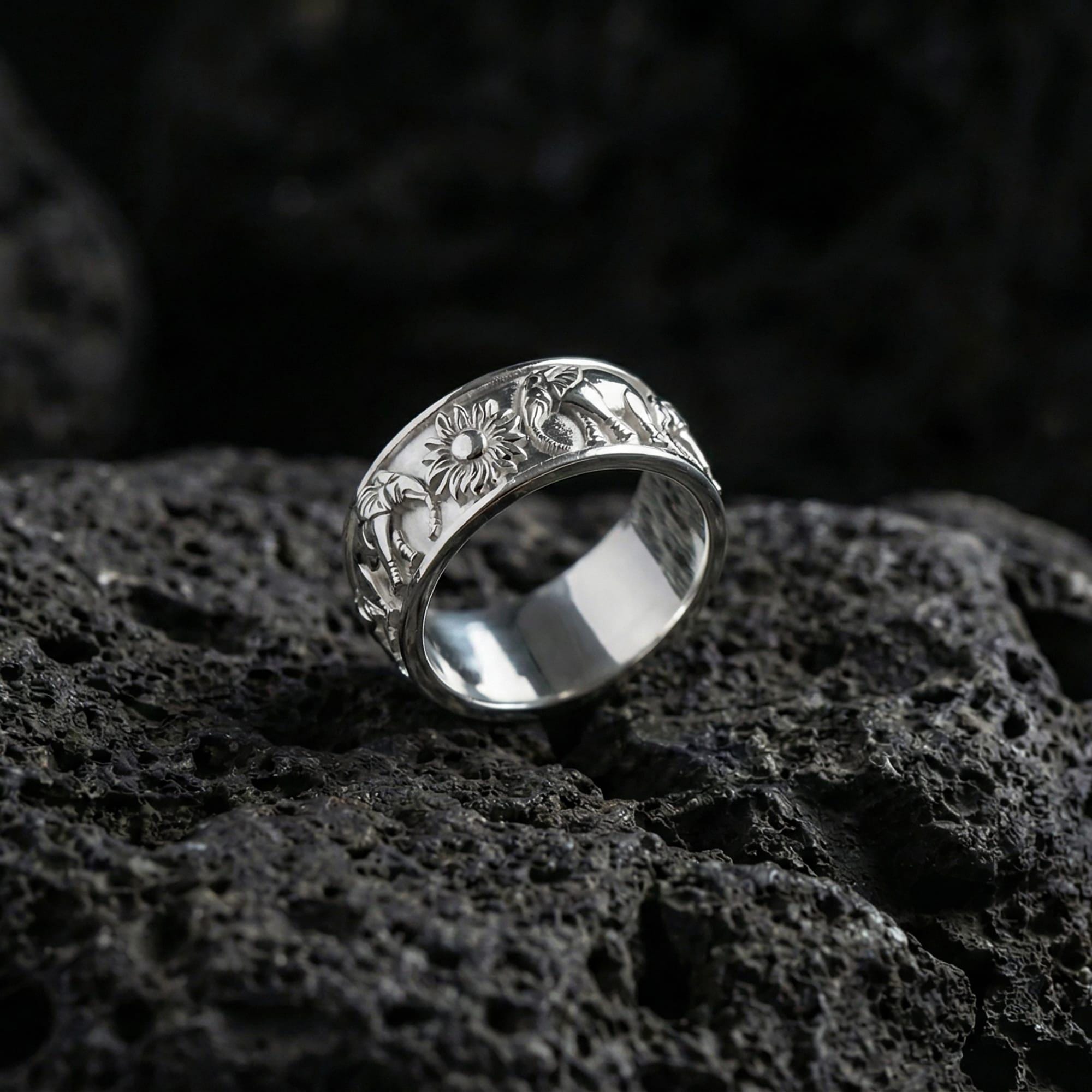 Polished silver prism facet wedding band ring displayed on volcanic stone background highlighting crisp angular pattern and reflective edges