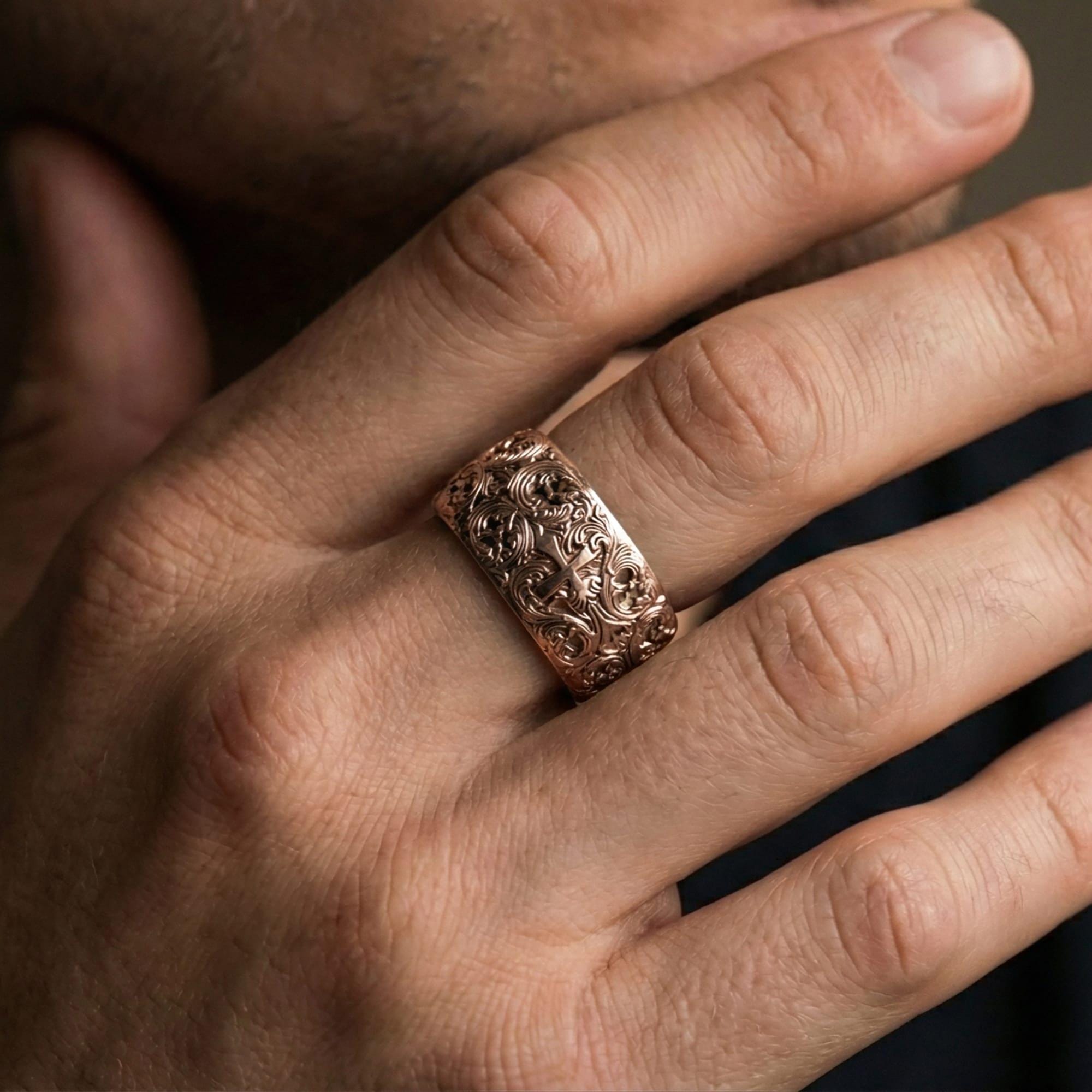 Rose gold plated ornate cross band ring worn on a finger, lifestyle image highlighting elegant rose tone and the ornate cross detailing as a refined statement band.