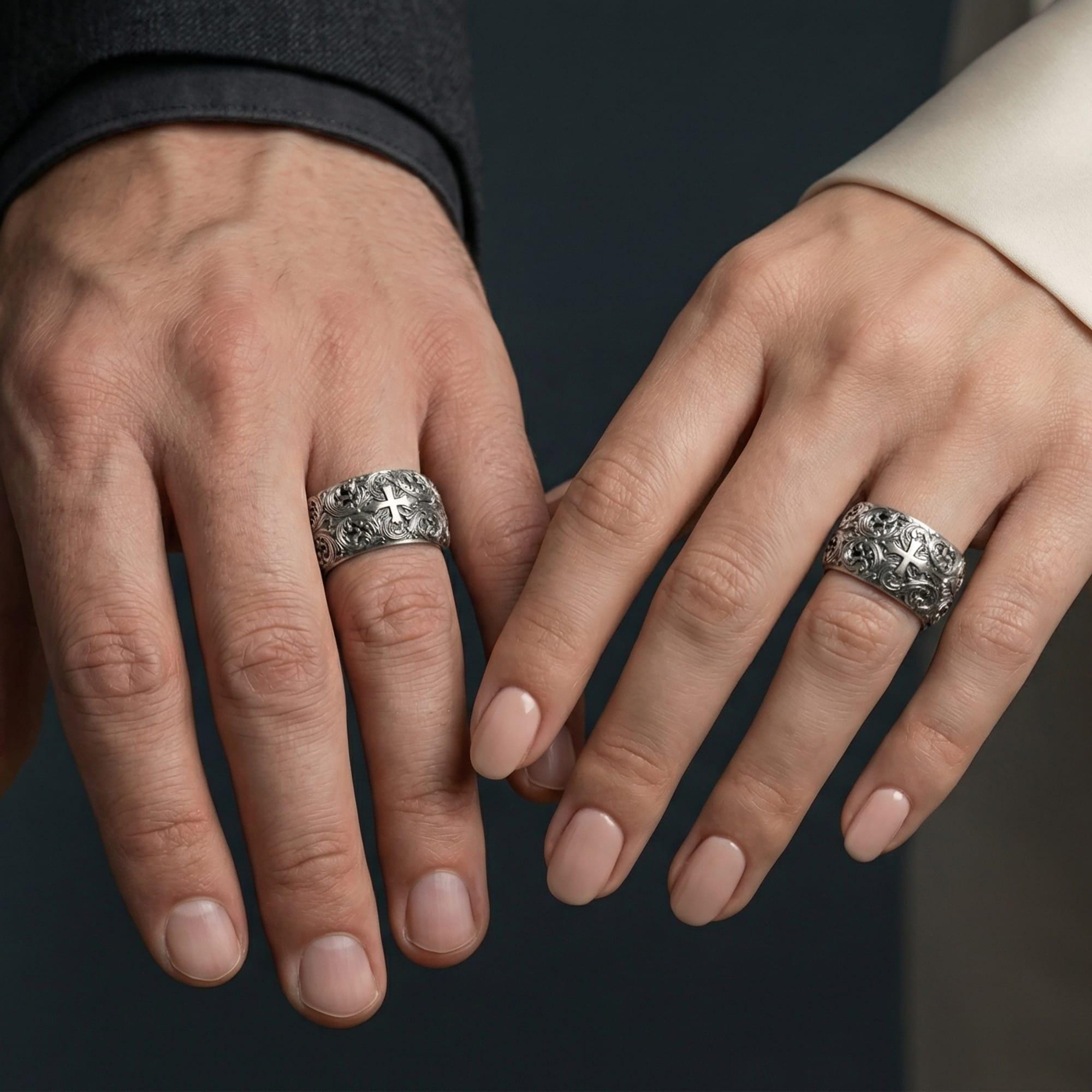 Oxidized sterling silver ornate cross band ring worn on a finger on a man and woman, lifestyle wear image showing bold sculpted depth and vintage-style contrast in natural light.