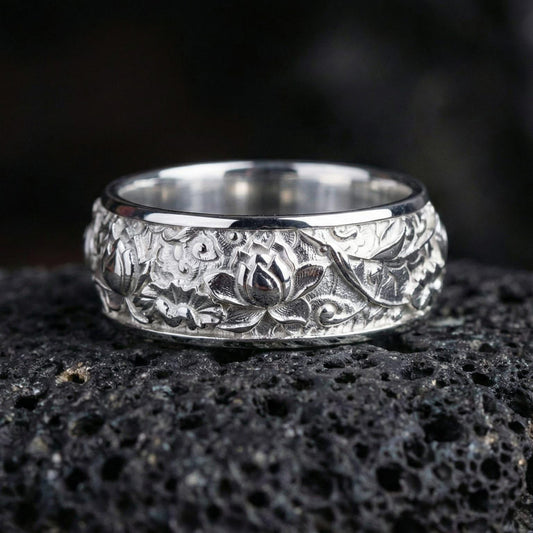 Polished silver lotus blossom sterling silver band ring displayed on volcanic stone background highlighting crisp engraving depth and clean edges