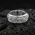 Load image into Gallery viewer, Polished silver rotating ancient Greek crowd wedding band on volcanic stone background highlighting crisp sculpted figures and depth
