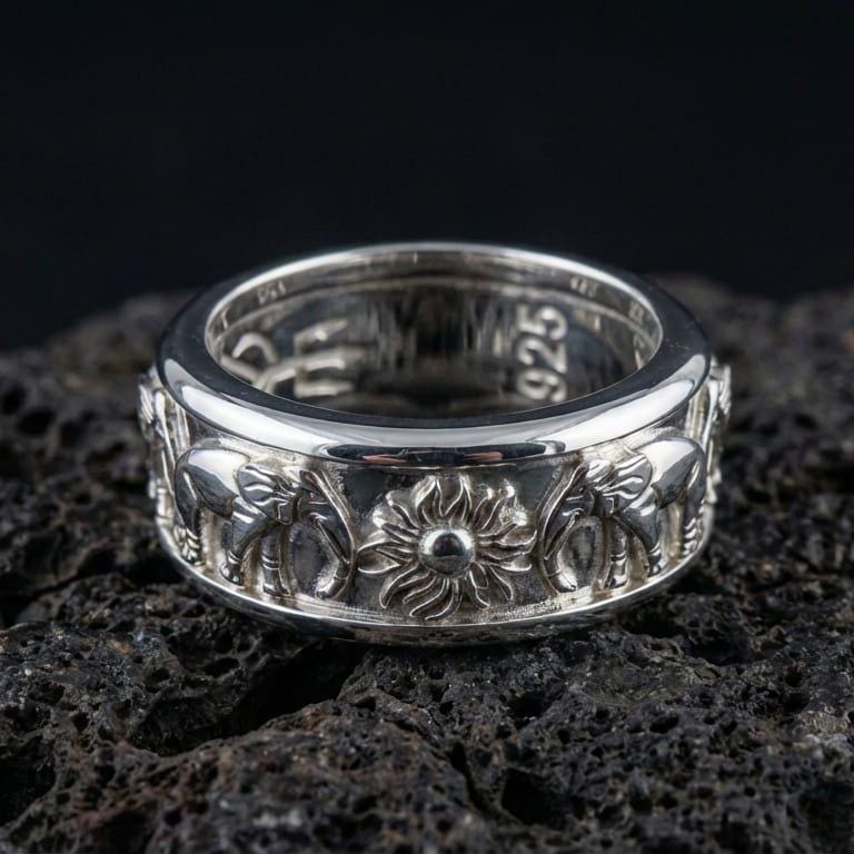 Polished silver spinning elephant wedding band displayed on volcanic stone background highlighting smooth comfort-fit edges and detailed animal relief