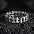 Load image into Gallery viewer, Oxidized steampunk chain link band ring photographed on volcanic rock, featuring industrial motorcycle chain texture and rugged mechanical detailing
